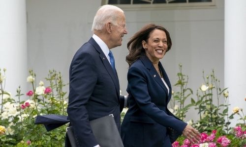 President Joe Biden and Vice President Kamala Harris smile as they walk off after an event updating.